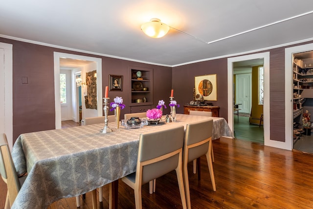 dining room featuring built in features, dark wood finished floors, and crown molding