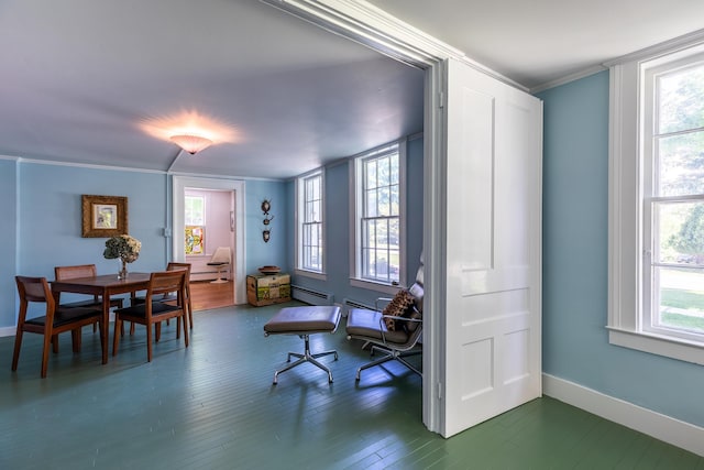dining area featuring baseboard heating, crown molding, baseboards, and wood finished floors