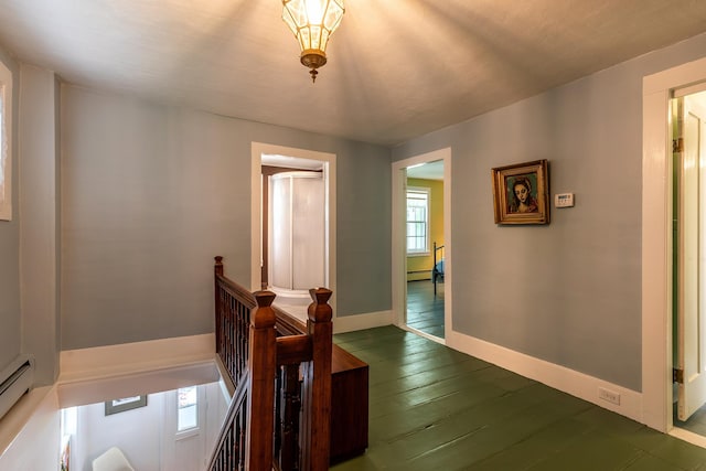 corridor featuring dark wood-style floors, an upstairs landing, baseboards, and a baseboard radiator