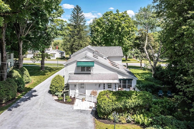 view of front facade with covered porch, driveway, and a shingled roof