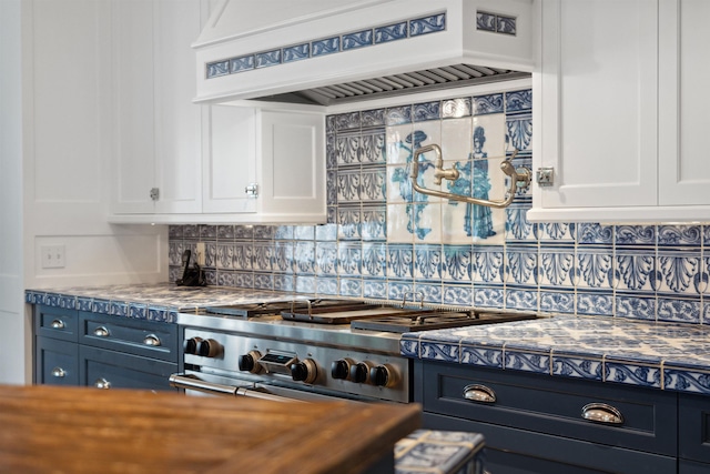 kitchen featuring custom range hood, blue cabinetry, tasteful backsplash, cooktop, and white cabinetry