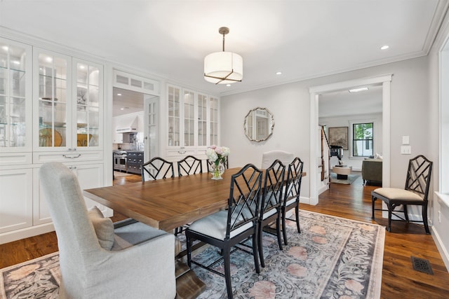 dining room with dark hardwood / wood-style flooring and crown molding