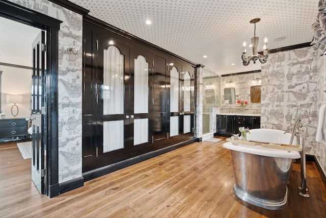 interior space with french doors, a notable chandelier, light hardwood / wood-style floors, decorative light fixtures, and ornamental molding