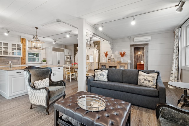 living room featuring wooden walls, light wood-type flooring, rail lighting, and a wall unit AC