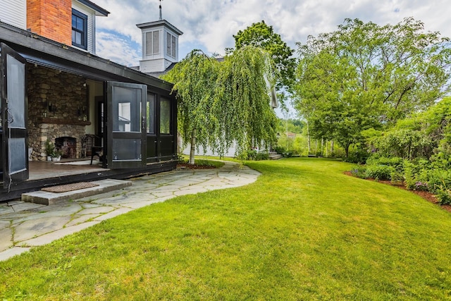 view of yard with an outdoor stone fireplace and a sunroom