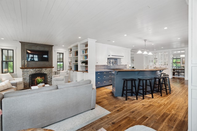 living room featuring a fireplace, ornamental molding, light wood-type flooring, and wooden ceiling