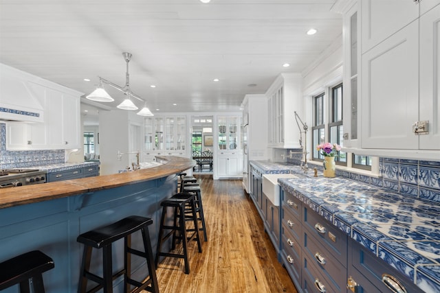 kitchen featuring white cabinets, pendant lighting, and wood counters