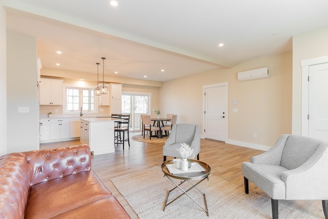 living room with sink, a wall mounted air conditioner, and light hardwood / wood-style flooring