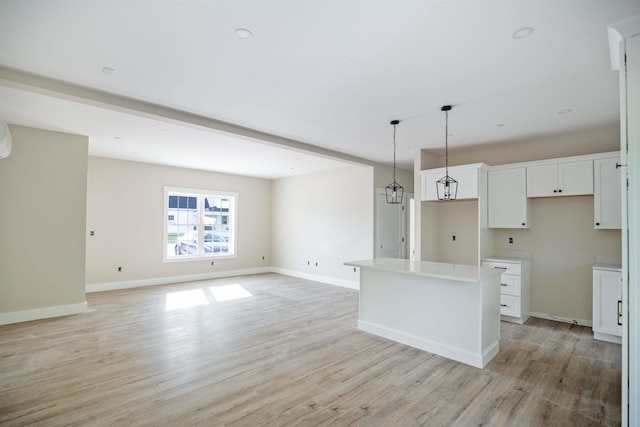 kitchen featuring hanging light fixtures, a kitchen island, white cabinets, and light hardwood / wood-style flooring