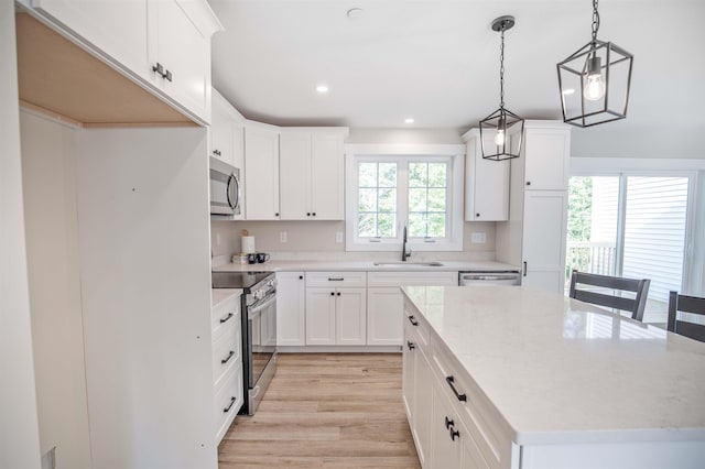 kitchen featuring decorative light fixtures, white cabinetry, sink, a center island, and stainless steel appliances