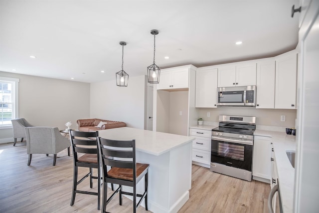 kitchen featuring stainless steel appliances, white cabinetry, a center island, and decorative light fixtures