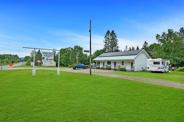 view of front facade with a front lawn, solar panels, and driveway