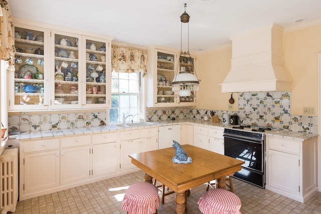 kitchen with radiator heating unit, decorative light fixtures, sink, stove, and tile counters