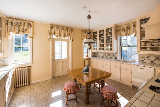 kitchen with radiator, decorative light fixtures, sink, backsplash, and tile counters