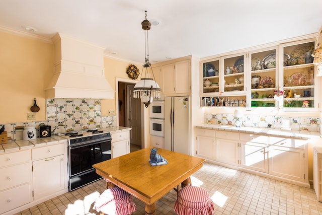 kitchen featuring range with gas cooktop, hanging light fixtures, fridge, tile counters, and white oven