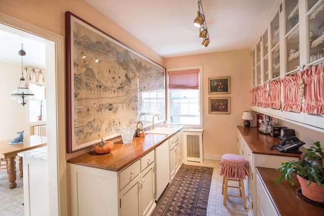 kitchen with rail lighting, sink, radiator heating unit, and white cabinets