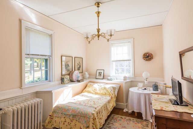 bedroom with hardwood / wood-style floors, radiator heating unit, and a chandelier