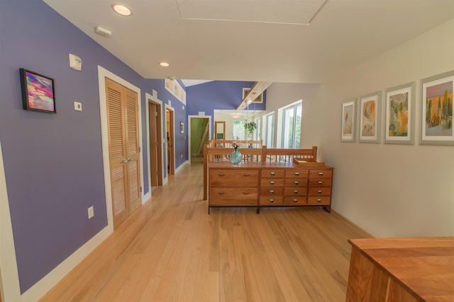 hallway with lofted ceiling and light hardwood / wood-style flooring