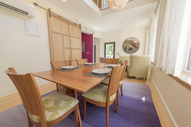 dining area featuring a barn door, a wall mounted AC, and wood-type flooring