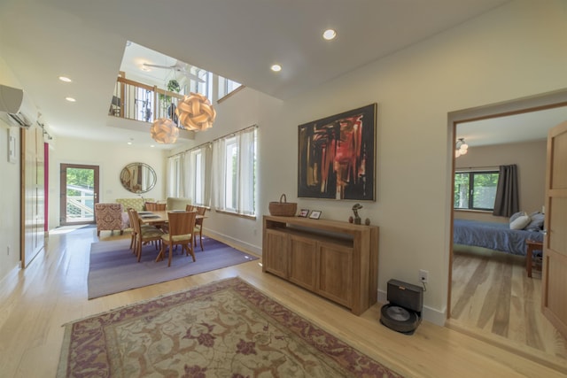 dining space featuring light hardwood / wood-style flooring, a wealth of natural light, and a wall unit AC