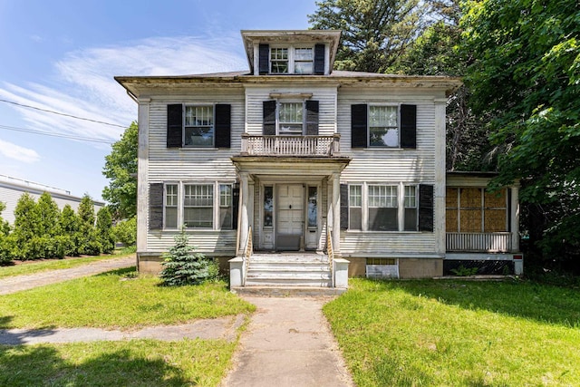 italianate home featuring a balcony and a front lawn