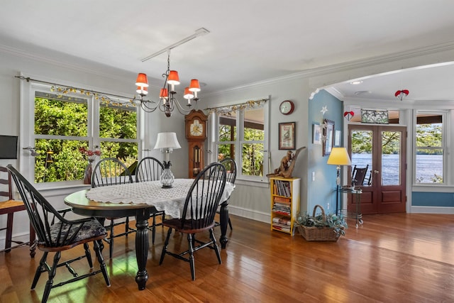 dining room with a healthy amount of sunlight, hardwood / wood-style flooring, crown molding, and french doors