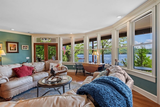 living room featuring hardwood / wood-style floors, a water view, ornamental molding, and a wealth of natural light