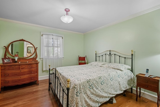 bedroom with crown molding, baseboards, and wood finished floors