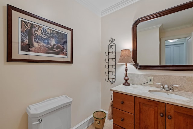 bathroom with ornamental molding, toilet, vanity, and baseboards