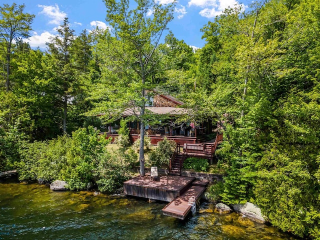 dock area featuring a forest view, stairway, and a deck