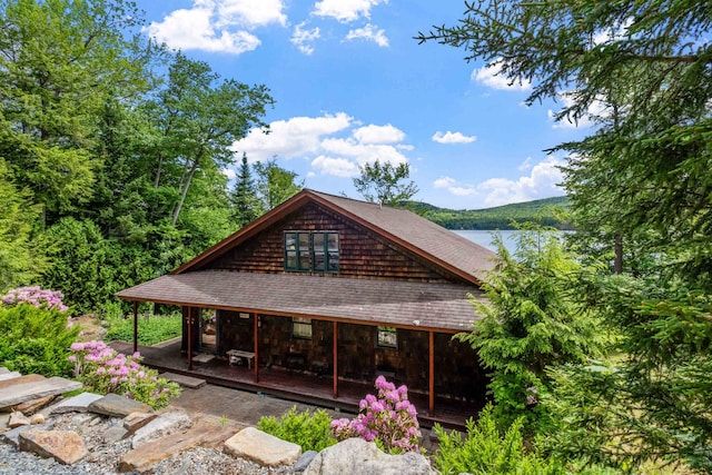 rear view of property featuring a shingled roof and a porch