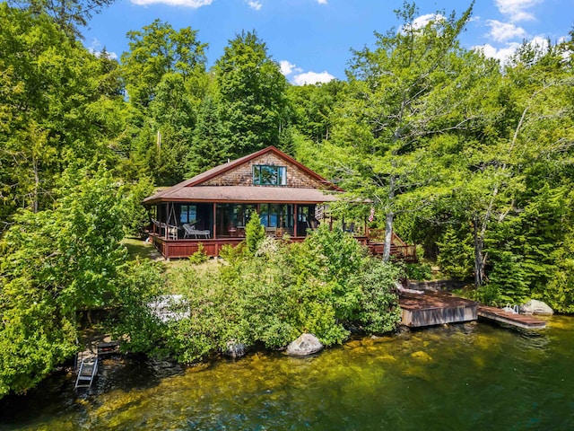 view of front of property featuring a deck with water view and a dock