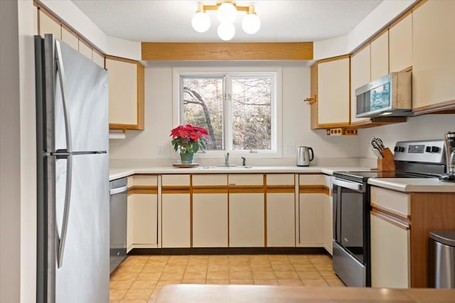 kitchen with a sink, a textured ceiling, stainless steel appliances, and light countertops