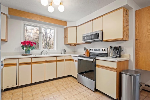 kitchen with a textured ceiling, appliances with stainless steel finishes, light countertops, and a sink