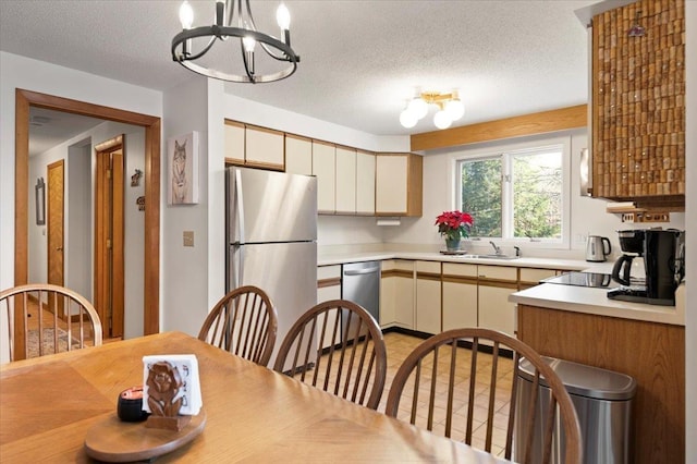 kitchen featuring appliances with stainless steel finishes, an inviting chandelier, light countertops, a textured ceiling, and a sink