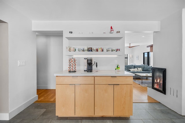 kitchen featuring light brown cabinetry, kitchen peninsula, and dark tile patterned floors