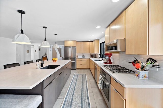 kitchen featuring appliances with stainless steel finishes, sink, a kitchen bar, a large island, and light brown cabinets