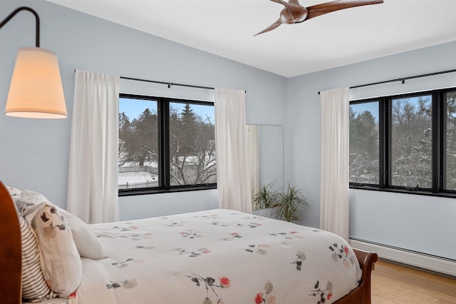 bedroom with a baseboard heating unit, vaulted ceiling, hardwood / wood-style floors, and ceiling fan