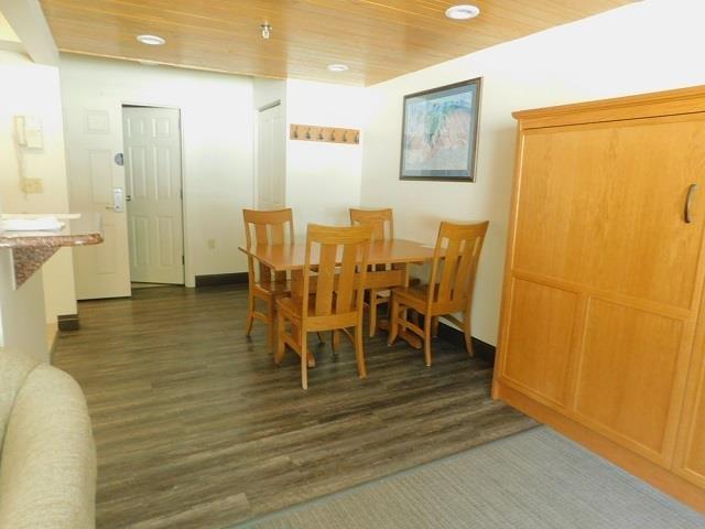 dining room with dark wood-type flooring and wooden ceiling