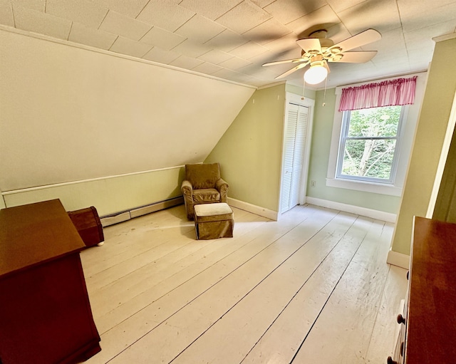 additional living space featuring light wood-type flooring, vaulted ceiling, ceiling fan, and a baseboard radiator