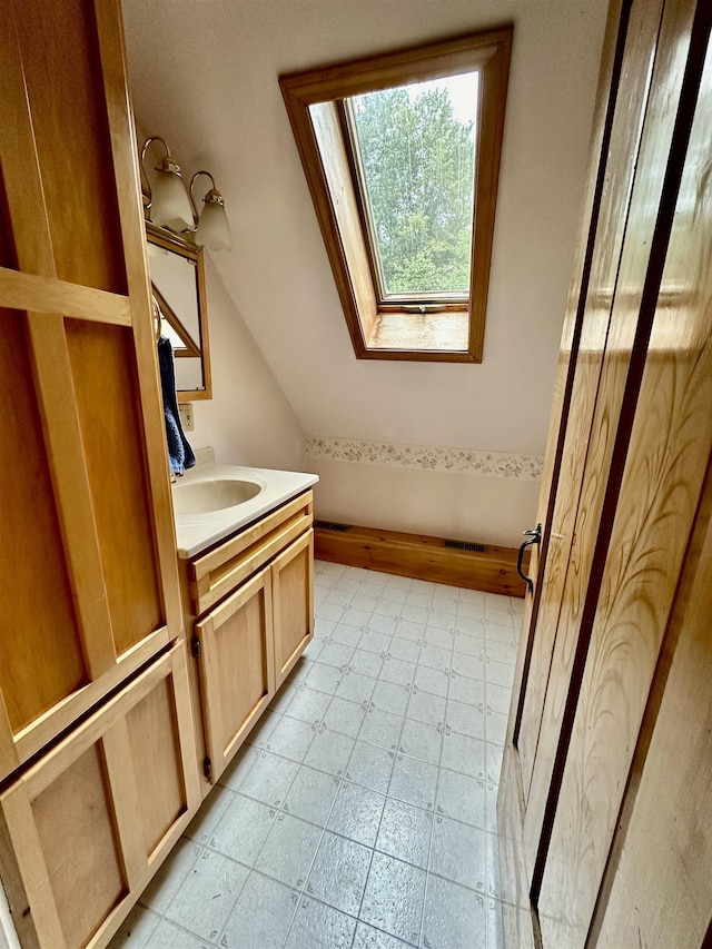 bathroom with vanity and lofted ceiling with skylight