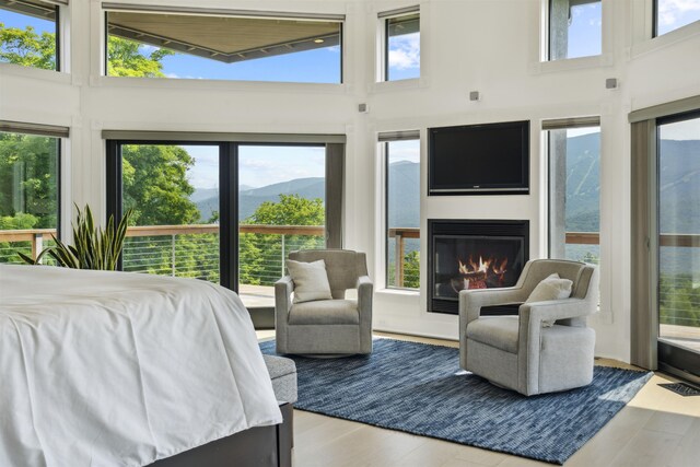 bedroom with light hardwood / wood-style floors, a high ceiling, and multiple windows