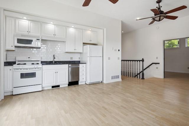 kitchen with light wood-type flooring, backsplash, white appliances, sink, and white cabinetry