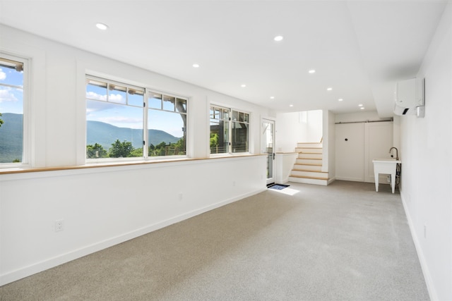 interior space featuring a wall unit AC, light carpet, plenty of natural light, and sink