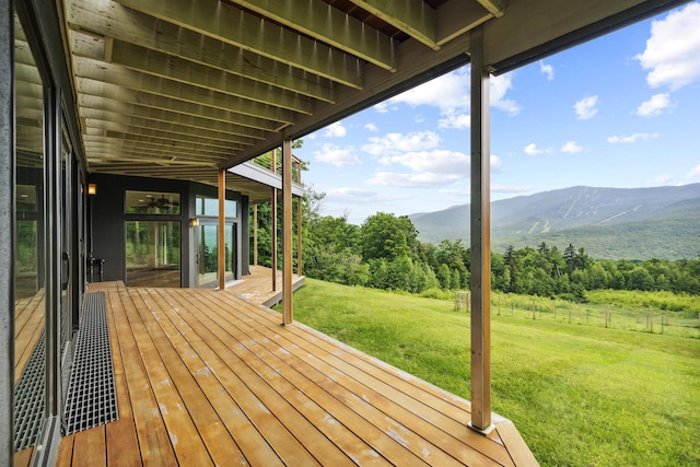 wooden terrace featuring a lawn and a mountain view