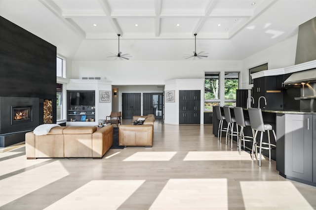 living room with beamed ceiling, a towering ceiling, a fireplace, and coffered ceiling