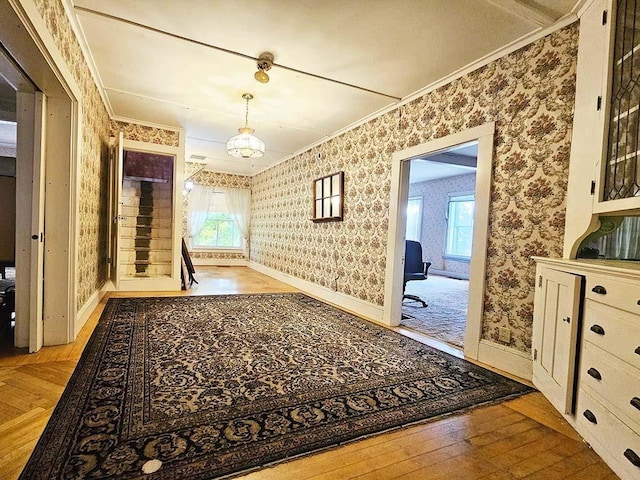 interior space featuring baseboards, crown molding, hardwood / wood-style floors, and wallpapered walls