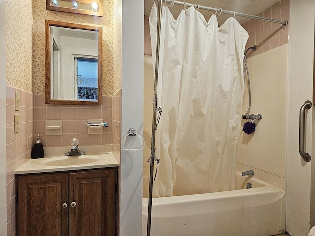 full bathroom featuring wallpapered walls, shower / bath combo, tile walls, and wainscoting