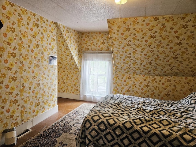 bedroom featuring wallpapered walls, baseboards, and a textured ceiling