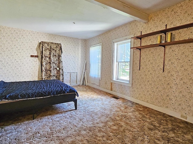 unfurnished bedroom with carpet floors, beam ceiling, visible vents, and wallpapered walls